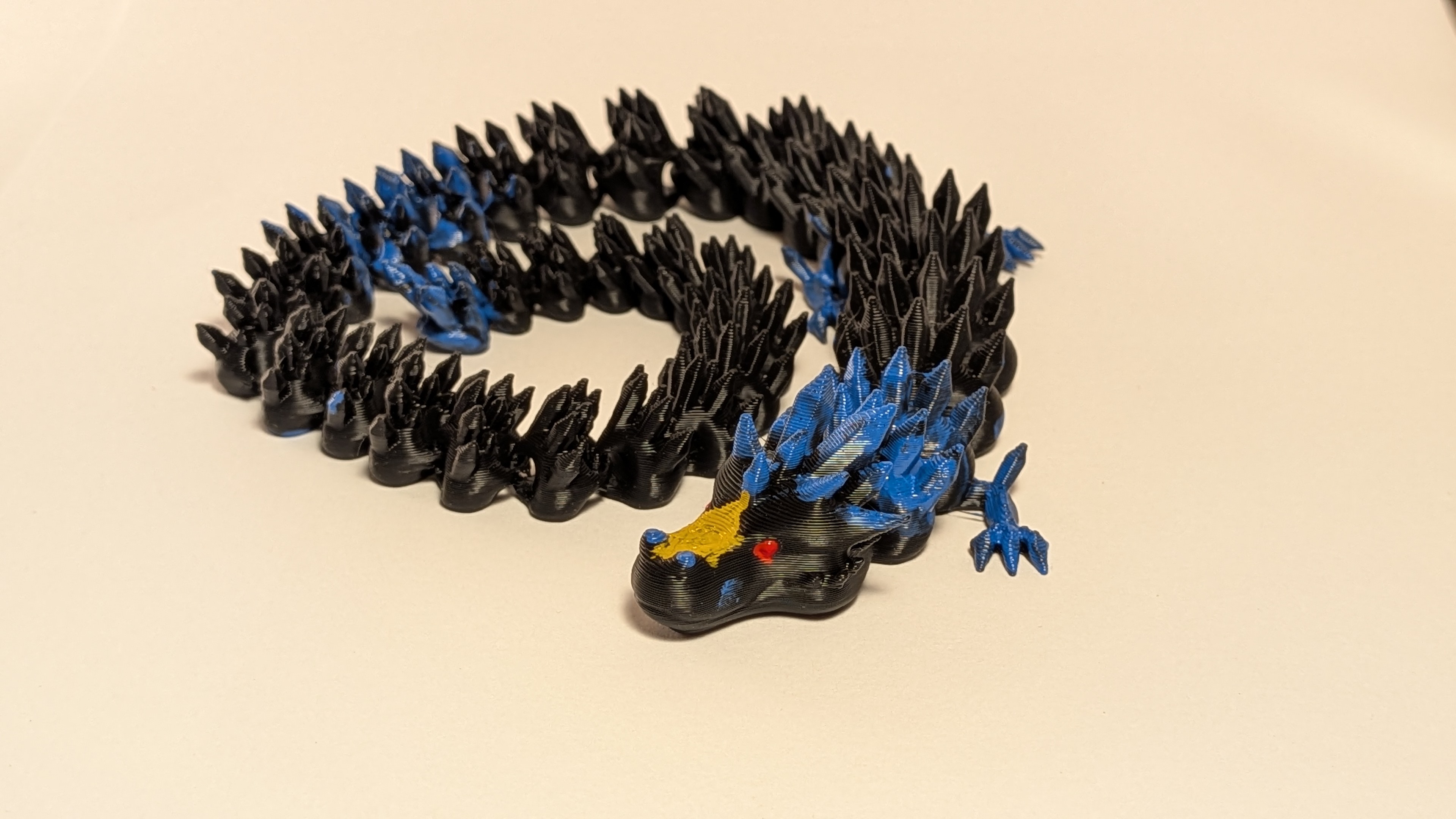 Large black and blue 3D printed articulated dragon coiled up