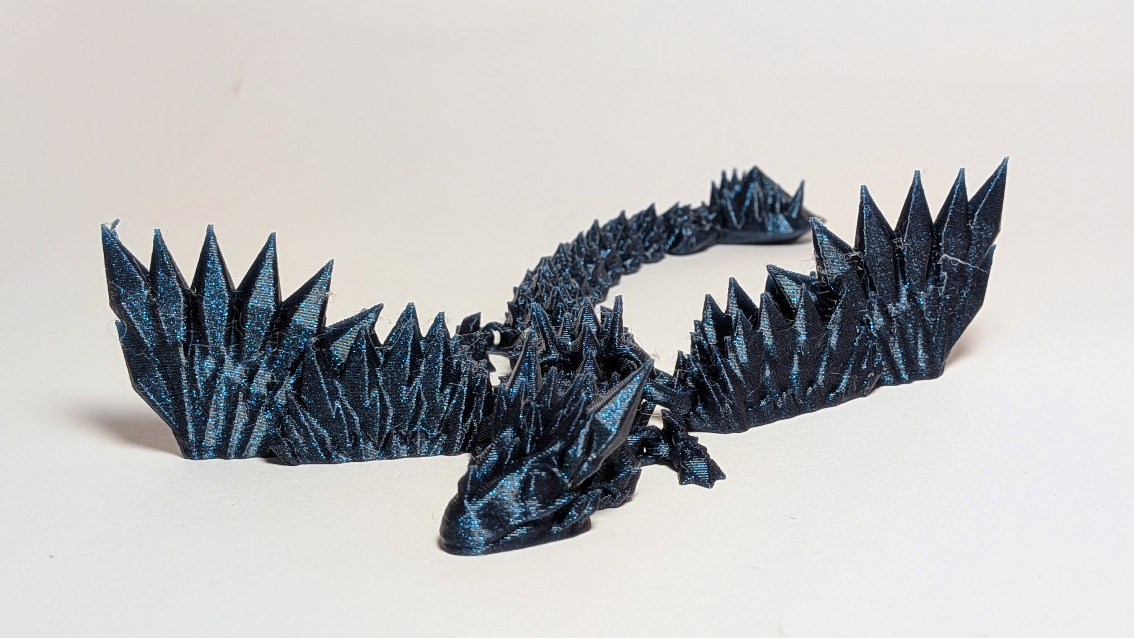 Deep blue glittery 3D printed articulated galaxy dragon with crystal spines